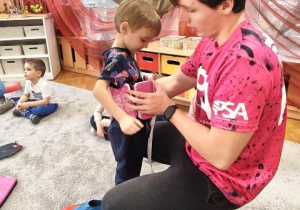 Trener zakłada dziecku pas wypornościowy.