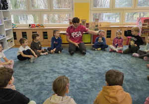 Instruktor pływania rozmawia z dziećmi na temat bezpieczeństwa w wodzie i nad morzem.