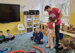 Instruktor pływania wyjaśnia jak prawidłowo zakładać kamizelkę do pływania.