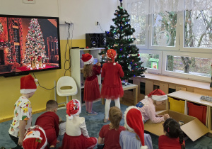 Dziewczynki ubierają choinkę - zakładają na gałązki piękne ozdoby świąteczne.