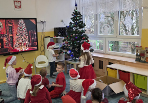 Kolejne dzieci wieszają piękne bombki na grupową choinkę.