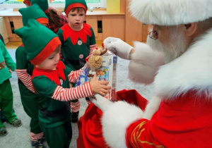 Dzieci- elfiki odbierają świąteczne upominki do Mikołaja.