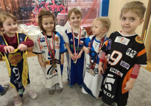 Dzieci prezentują się w koszulkach klubowych, udekorowane medalami.
