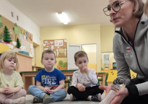 Pani Agata prezentuje dzieciom jeden z pucharów wywalczony w czasie rozgrywek siatkarskich.