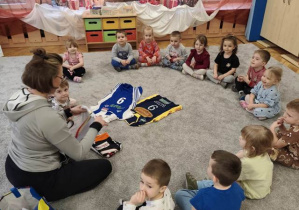 Pani Agata rozkłada pośrodku dywanu koszulki siatkarskie różnych klubów w których była zawodniczką.