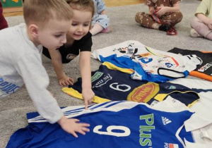 Dzieci oglądają koszulki klubowe.