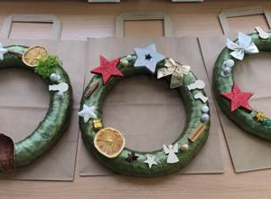 Prace dzieci- na stole położone są trzy stworzone przez dzieci wianki bożonarodzeniowe.