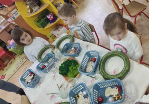 Dzieci słuchają wypowiedzi prowadzącej spotkanie, która wyjaśnia jak należy wykonać zadanie.