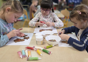 Dziewczynki dekorują pierniczki wg własnego pomysłu.