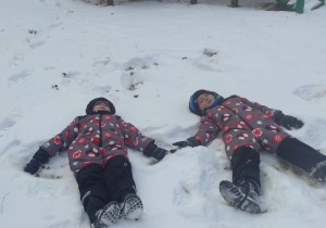 Chłopcy robią "aniołka " na śniegu.