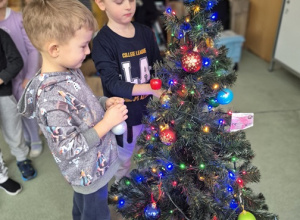 Chłopcy ubierają wspólnie choinkę.