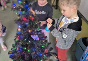 Chłopcy ubierają choinkę.