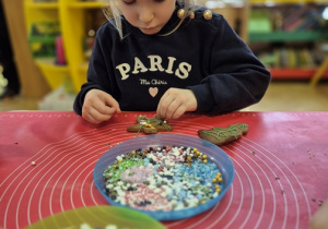 Dziewczynka z radością dekoruje swoje pierniki.