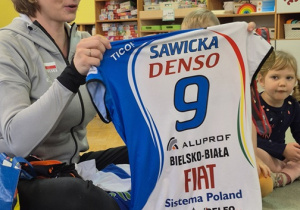 Siatkarka prezentuje dzieciom swoje koszulki reprezentacyjne.