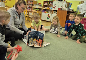 Siatkarka czyta dzieciom książkę w przedszkolu.