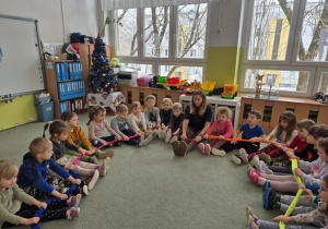 Grupa „Mróweczek” odkrywa różne właściwości gumy sensorycznej podczas zabawy na dywanie.