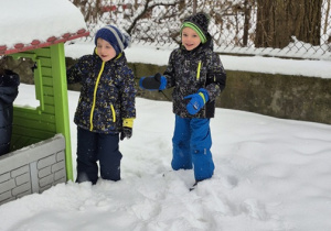 Chłopcy chowają się za domkiem w ogrodzie przedszkolnym.