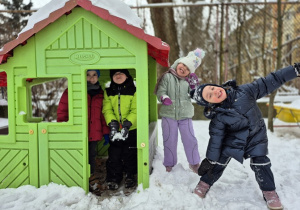 Dzieci bawią się w domku w ogródku przedszkolnym.
