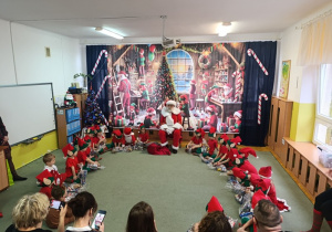 zieci radośnie śpiewają piosenki dla Mikołaja, witając go uśmiechami i głośnym świątecznym śpiewem.