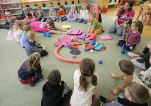 Dzieci zastanawiają się do czego służy deska, którą trzyma w dłoniach instruktor.