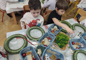 Dzieci wykonują stroiki świąteczne z dostępnych materiałów.