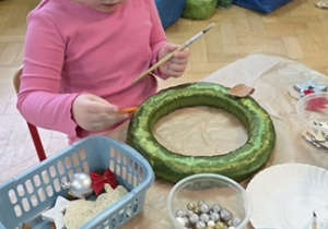 Dziewczynka wykonuje stroik świąteczny wg własnego pomysłu.