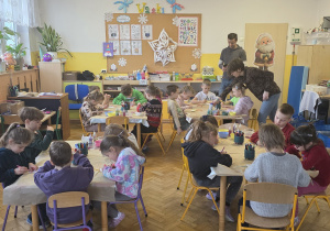 Dzieci siedzą przy stolikach i pracują wg wytycznych Pani Kasi.