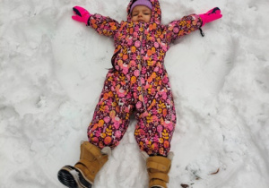 Dziewczynka robi na śniegu aniołka.