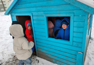 Dzieci schowały się do niebieskiego domku ogrodowego.