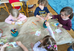 Dzieci kolorują mazakami wizytówki do prezentów.