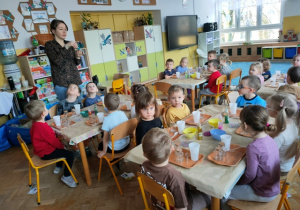 Pani Kasia prezentuje grupie elementy zdobnicze, które można włożyć do szklanych pojemników.