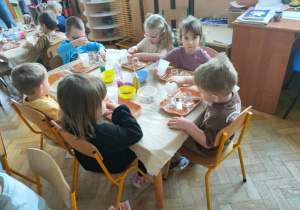 Dzieci nalewają wodę do szklanych naczyń.