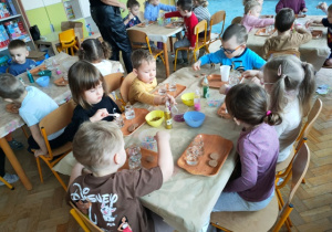 Dzieci wkładają do naczyń wybrane przez siebie elementy zdobnicze- susz kwiatowy, żelowe perełki oraz brokat.