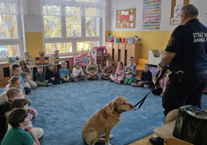 Funkcjonariusz Straży Miejskiej i jego psia towarzyszka witają się ze wszystkimi dziećmi.