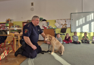 Funkcjonariusz pokazuje gdzie należy głaskać nie znajomego psa.