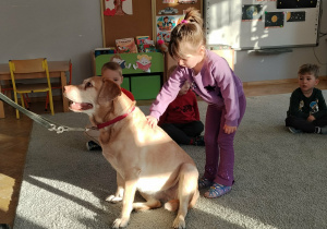 Chętne dzieci głaszczą pieska.