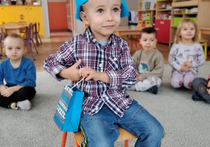 Chłopiec siedzi w koronie na krzesełku.