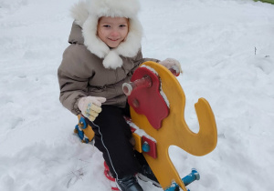 Dziewczynka jeździ na słoniku.