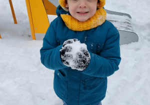 Chłopiec szykuje się do bitwy na śnieżki.
