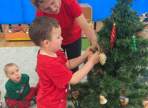 Chłopiec wiesza bombkę na choince.