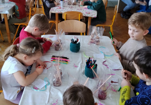 Dzieci pracują przy stolikach.