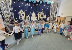 Dzieci trzymają się za ręce i idą po obwodzie koła w rytmie zimowej piosenki.