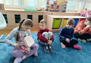 Dzieci ćwiczą prawidłowe szczotkowanie zębów z wykorzystaniem modelu szczęki.