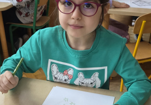 Dziewczynka koloruje listek, którym oznacza się produkty ekologiczne.