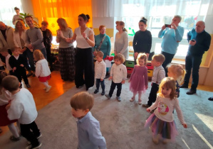 Dzieci wraz z seniorami bawią się przy muzyce.