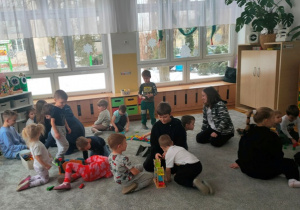 Dzieci i uczniowie bawią się wspólnie na dywanie.