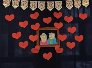 Dekoracja przygotowana na przedstawienie - napis: kochamy was oraz portret babci i dziadka.