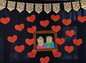 Dekoracja przygotowana na przedstawienie - napis: kochamy was oraz portret babci i dziadka.