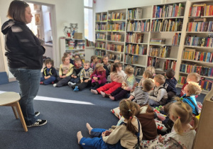 Dzieci siedzą na materacach i poduchach słuchają uważnie o czym będą zajęcia.