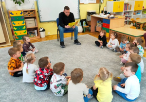 Dzieci słuchają bajki czytanej przez tatę dziewczynki ze starszej grupy.
